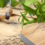 Wooden board with needles for acupuncture on table, closeup